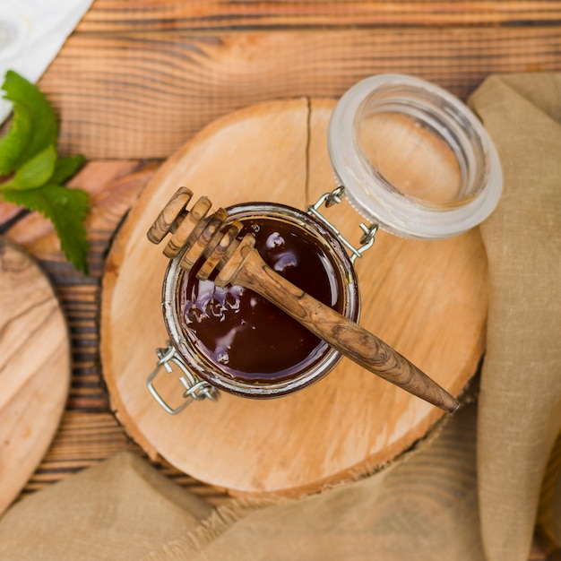 Top view glass jar full of honey with honey spoon