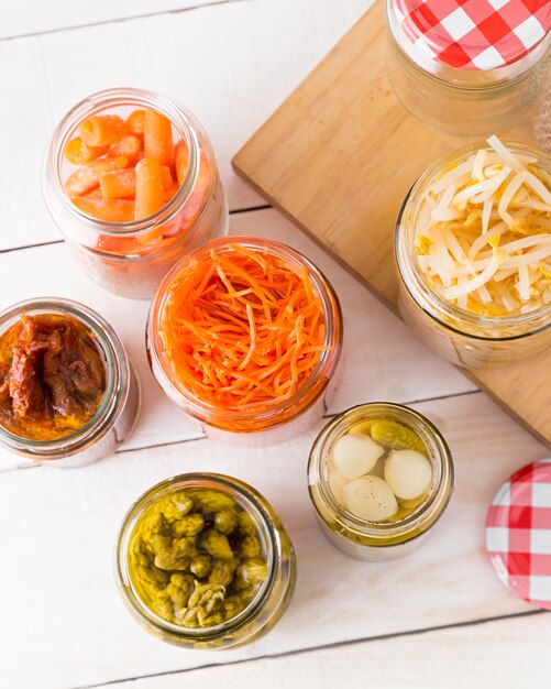 Top view of glass jars with baby carrots and other vegetables