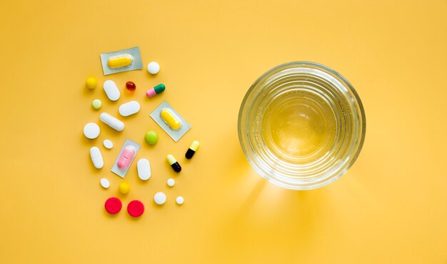 Top view of glass of water and multiple pills