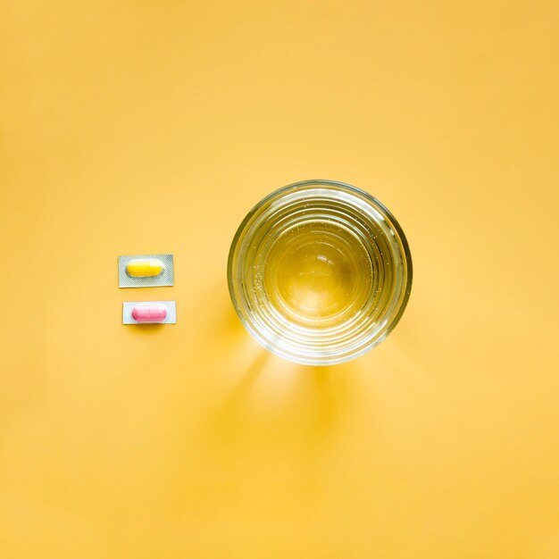 Top view of glass of water and pills in foil