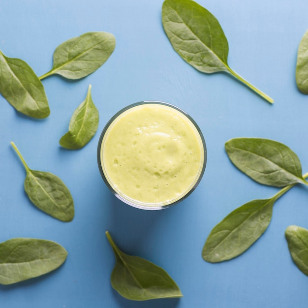 Top view glass with green smoothie and leaves