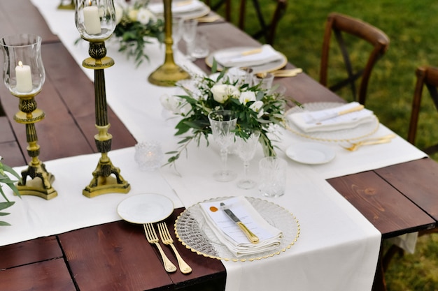 흰색 eustomas와 ruscus 부케와 야외 나무 테이블에 유리와 칼의 상위 뷰
