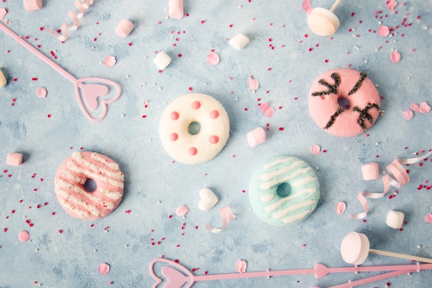 Top view of glazed doughnuts with assortment of candy