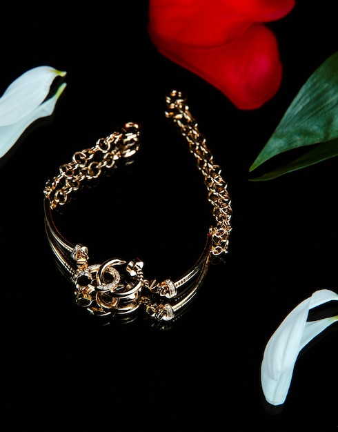 Top view of golden bracelet with diamonds on black wall