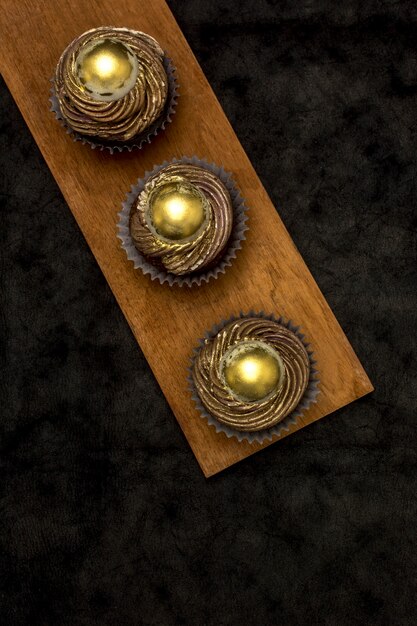 Top view of golden cupcakes on wooden board