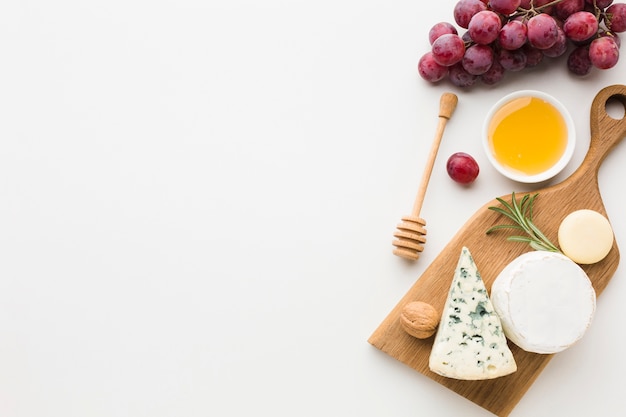 Top view gourmet assortment of cheese on wooden cutting board with copy space