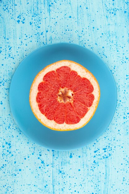 Free photo top view grapefruit ring round juicy mellow inside blue plate on the bright blue floor