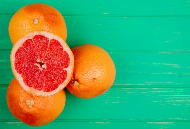 Top view of grapefruits on left side and green background with copy space