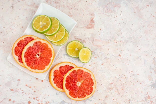 Free photo top view grapefruits slices lemon slices on white rectangular plate on nude table free space