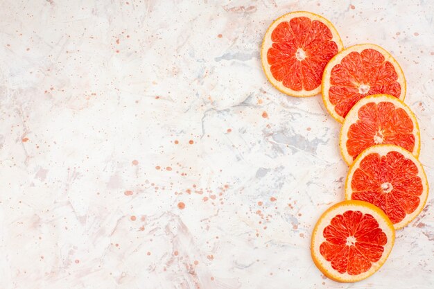 Top view grapefruits slices on nude surface with copy space