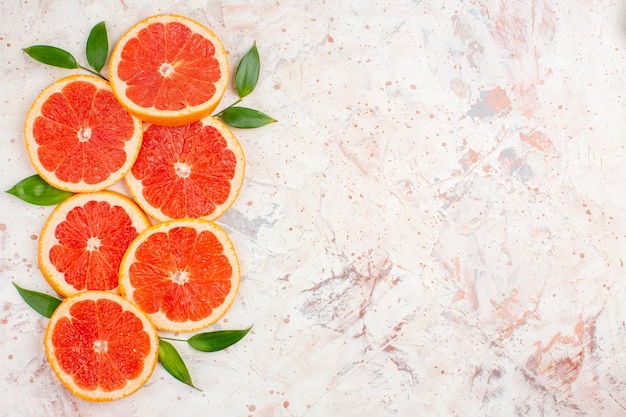 Free photo top view grapefruits slices with leaves on nude surface copy space