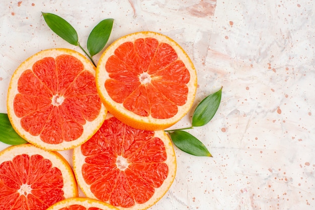 Top view grapefruits slices with leaves on nude surface free place