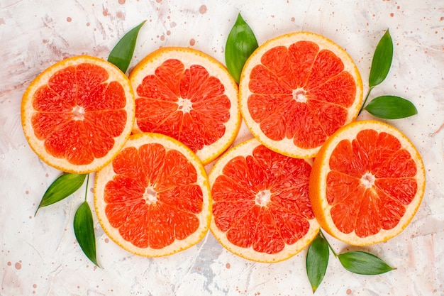 Top view grapefruits slices with leaves on nude surface