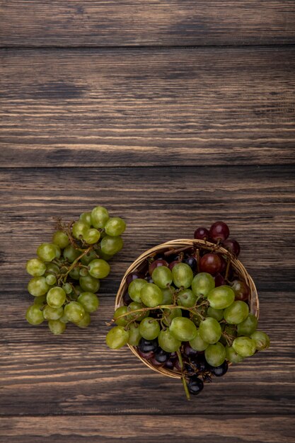 Top view of grapes in basket and on wooden background with copy space