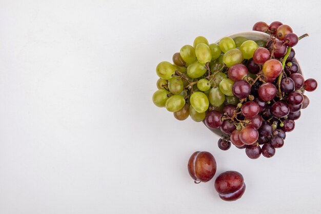 Top view of grapes in bowl on white background with copy space