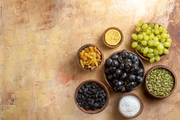 Top view of grapes bowls of bunches of grapes raisins sugar lemon pumpkin seeds