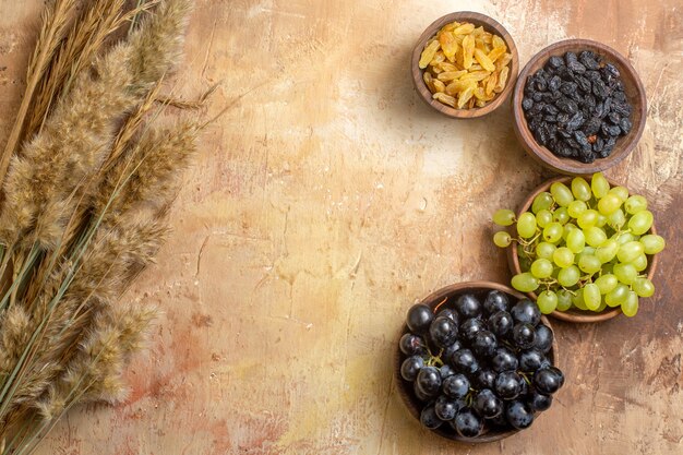 Top view of grapes grapes raisins in the bowls spikelets on the table