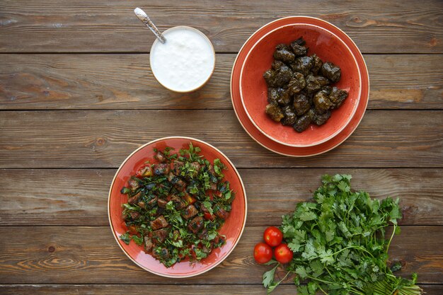 Top view of grapes leaves dolma and lamb pieces with herbs