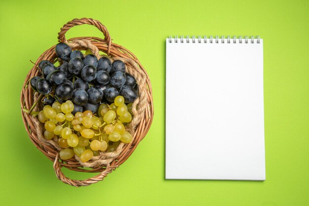 top view grapes white notebook bunches of grapes on the green table