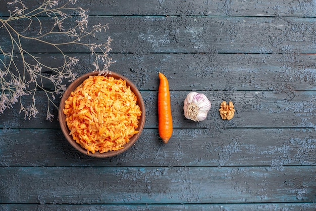 Top view grated carrot salad inside brown plate on dark-blue rustic desk health salad ripe vegetable color diet