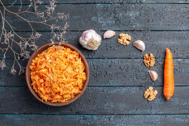 Top view grated carrot salad with garlic inside plate on dark-blue rustic desk health color salad ripe vegetable diet