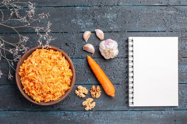 Top view grated carrot salad with garlic inside plate on a dark-blue rustic desk health salad ripe vegetable color diet