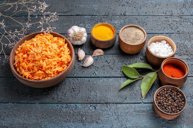 Top view grated carrot salad with garlic and seasonings on a dark-blue rustic desk health color salad vegetable diet ripe