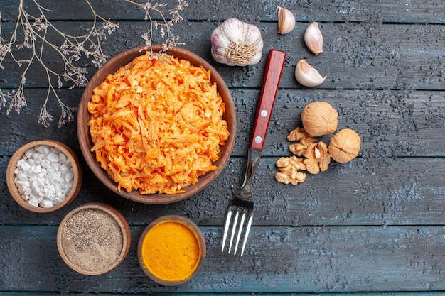 Top view grated carrot salad with garlic and seasonings on dark-blue rustic desk health color salad vegetable diet ripe