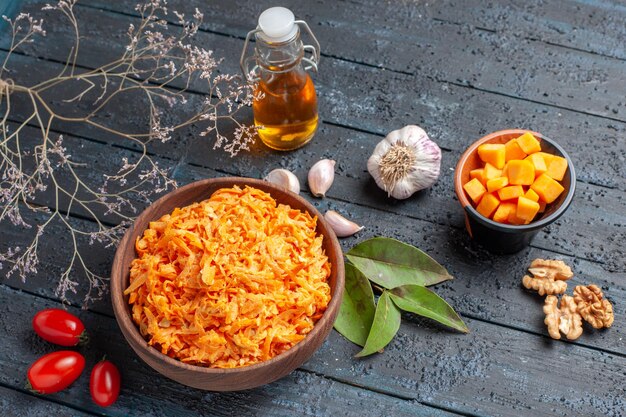 Top view grated carrot salad with garlic walnuts on dark background health diet orange color ripe salad