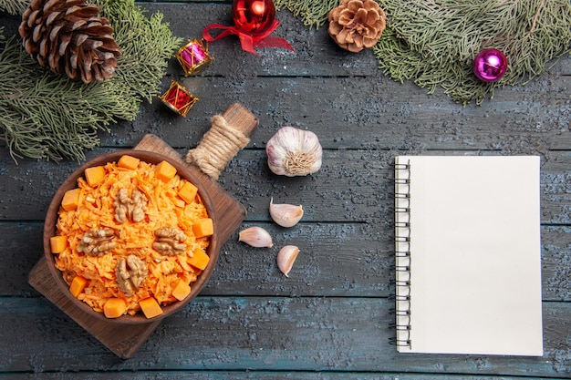 Top view grated carrot salad with walnuts on dark-blue desk health food salad color diet nut