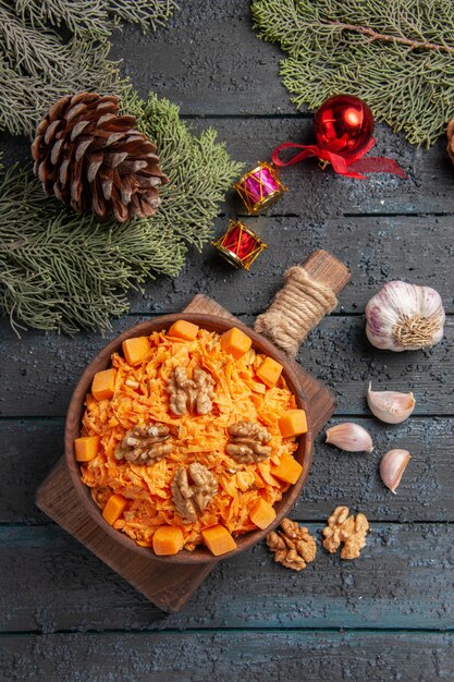 Top view grated carrot salad with walnuts and seasonings on dark blue desk health food salad color diet nut