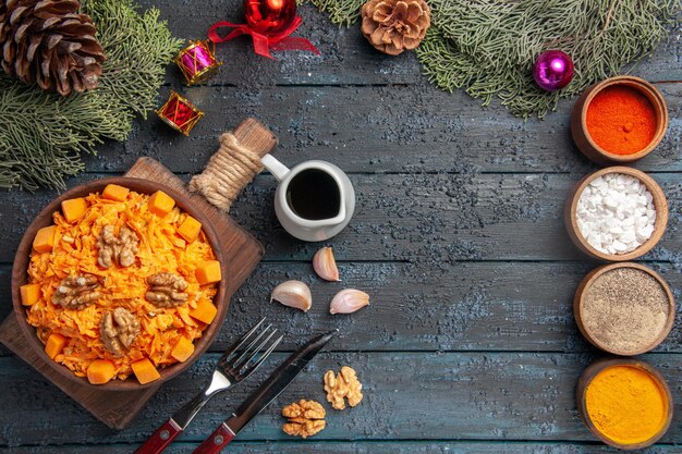 Top view grated carrot salad with walnuts and seasonings on dark-blue desk health food salad diet nuts color