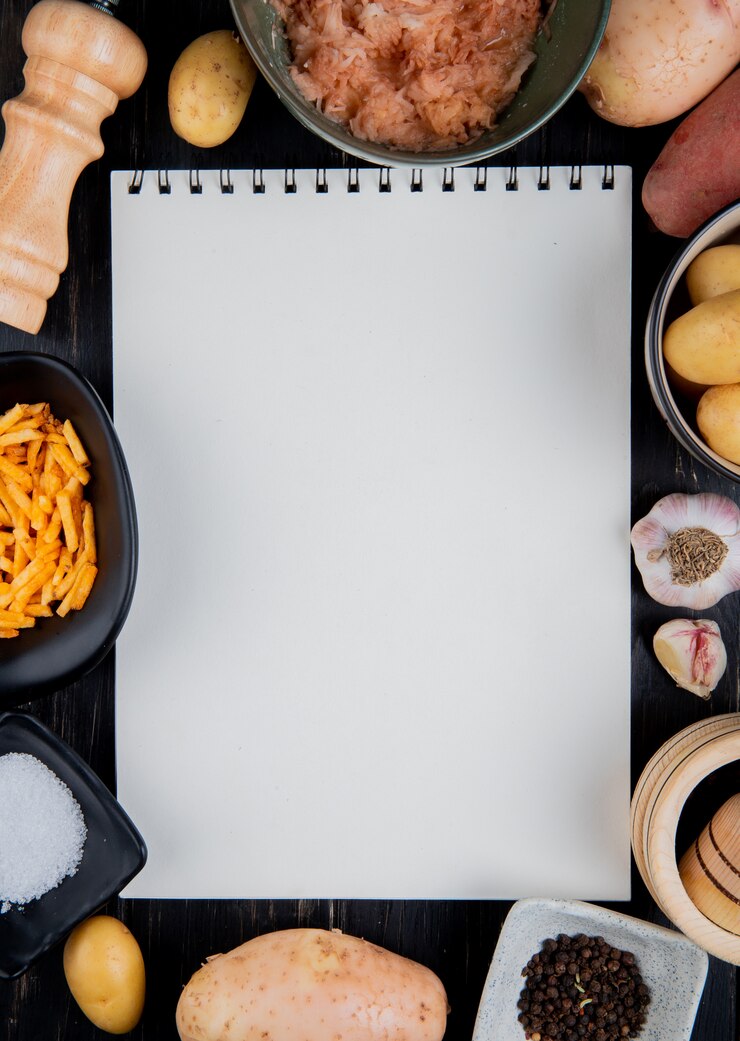 मुफ़्त फोटो top view of grated sliced and whole potatoes around note pad with salt black pepper on wooden surface with copy space