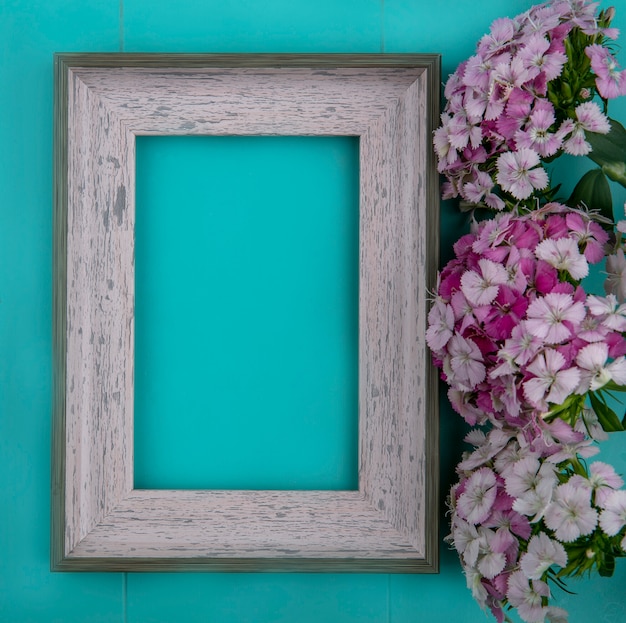 Top view of gray frame with light purple flowers on a light blue surface