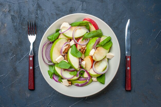진한 파란색 테이블에 접시 포크와 나이프에 상위 뷰 녹색 사과 샐러드
