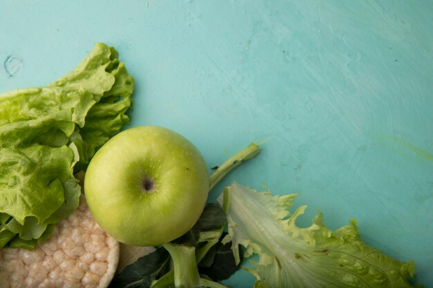 Top view green apple with lettuce crunchy crispbread and copy space on mint background