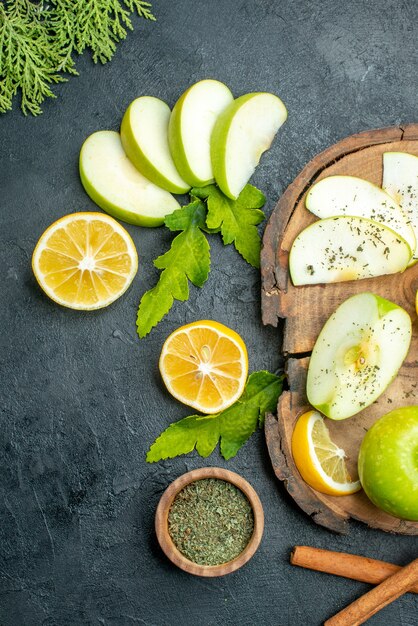 상단 보기 녹색 사과 계피 스틱 레몬과 사과 조각을 나무 판자에 검은 테이블에 자른 레몬 사과