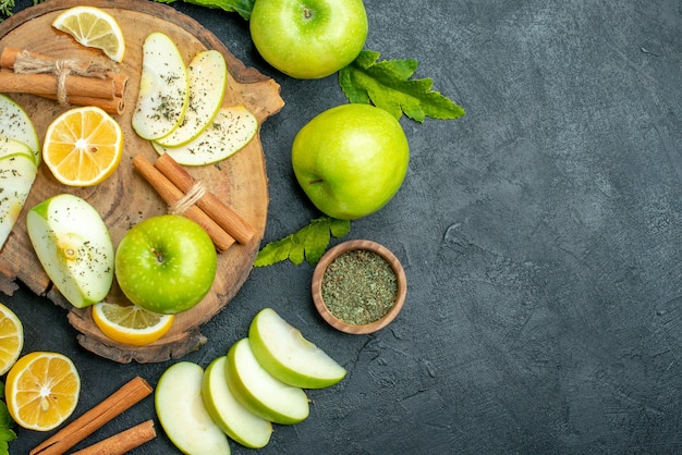 나무 판자에 있는 상위 뷰 녹색 사과 계피 스틱과 레몬 조각 사과 조각
