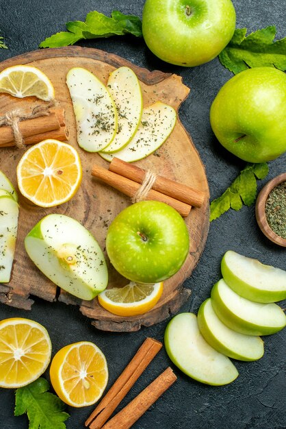 나무 판자에 있는 상위 뷰 녹색 사과 계피 스틱과 레몬 조각 사과 조각