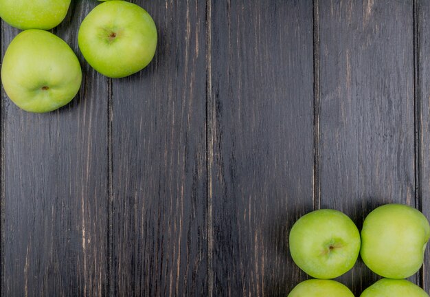 Free photo top view of green apples on sides on wooden background with copy space