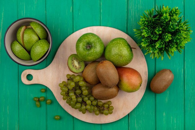 上面図緑の背景のスタンドにキウイ緑のブドウと梨と青リンゴ