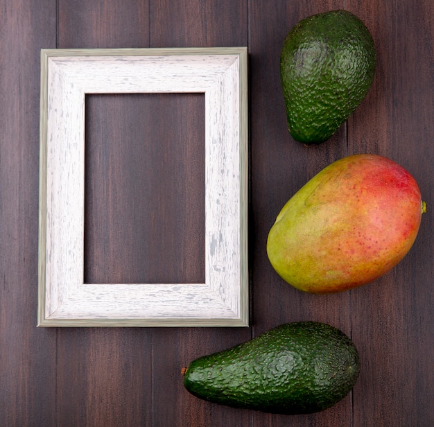 Foto gratuita vista dall'alto di avocado verde con mango su una superficie di legno