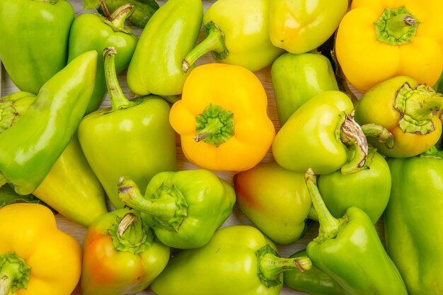 Top view green bell-peppers inside frame on a white table