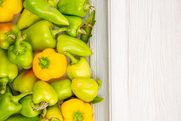 Top view green bell-peppers inside frame on white table