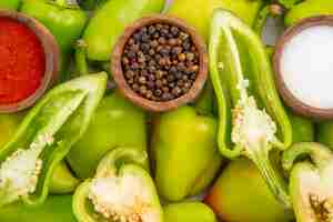 Free photo top view green bell-peppers inside frame with seasonings on a white table