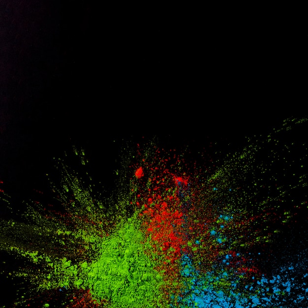 Top view of green,blue and red holi colored powder over black background