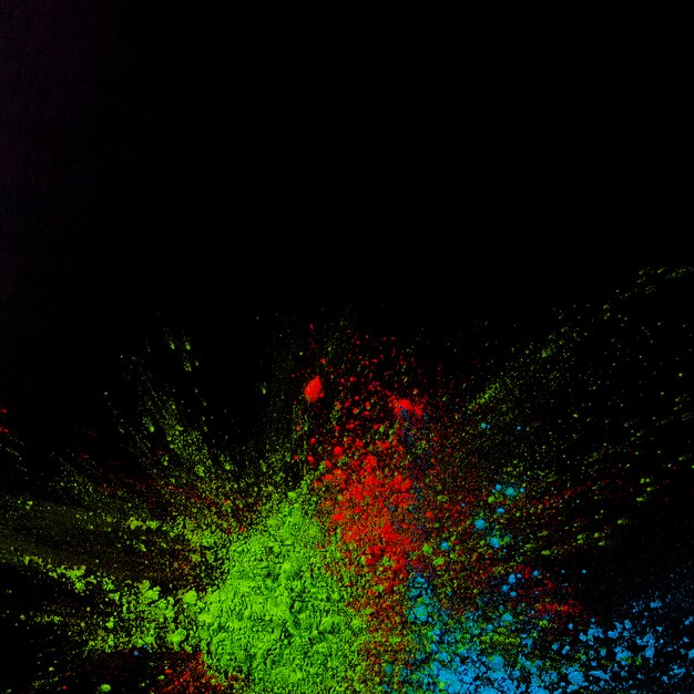 Top view of green,blue and red holi colored powder over black background