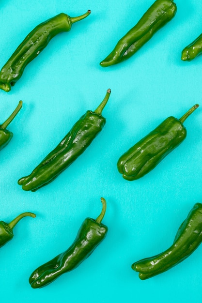 Free photo top view green chili pepper pattern on blue  vertical