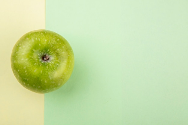 Вид сверху зеленого и свежего яблока на желтой и зеленой поверхности