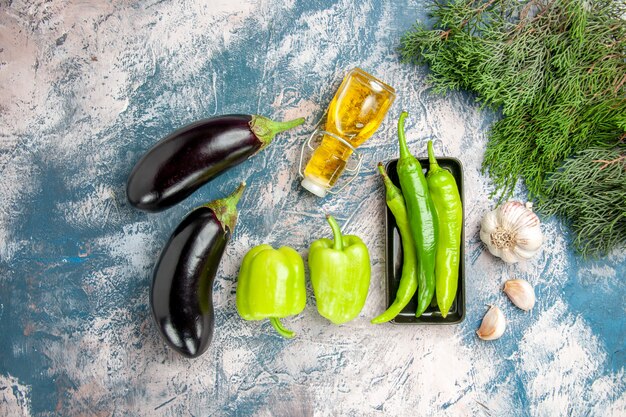 Top view green hot peppers on black plate garlic oil eggplants peppers on blue-white background